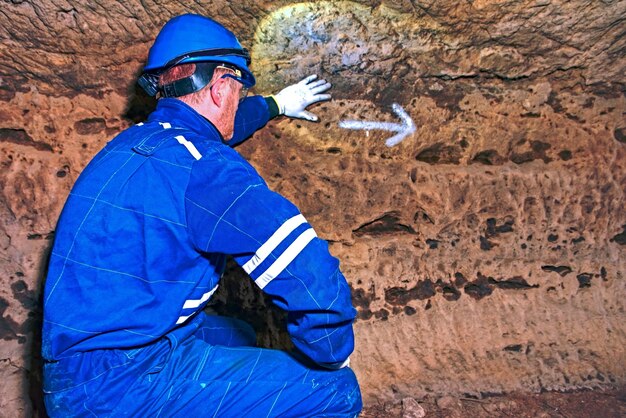 Foto uomo impiegato del tunnel sotterraneo in tuta di sicurezza e casco nel tunnel costruito per i ricchi in guerra