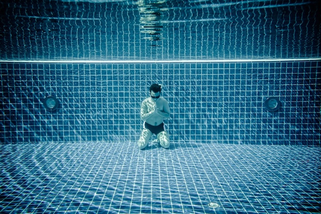 L'uomo sott'acqua in una piscina prega