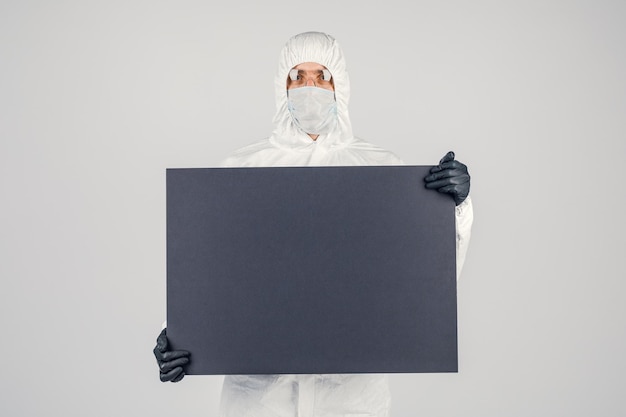 A man in a uniform and face mask holding a placard Concept of healthcare and medicine