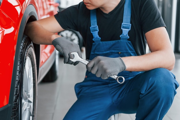 Man in uniform sits with wrench in hand near broken automobile
conception of car service