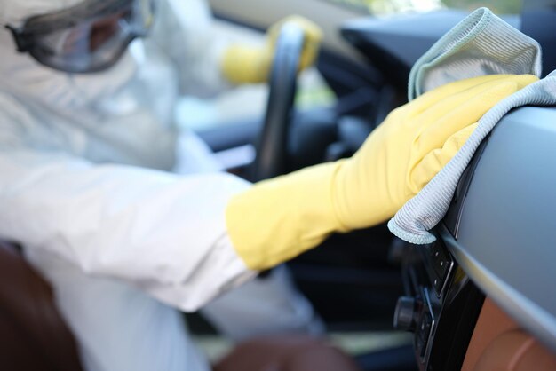 Foto un uomo in uniforme pulisce l'interno di un'auto con un asciugamano