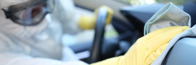 A man in uniform wipes the interior of a car with a towel