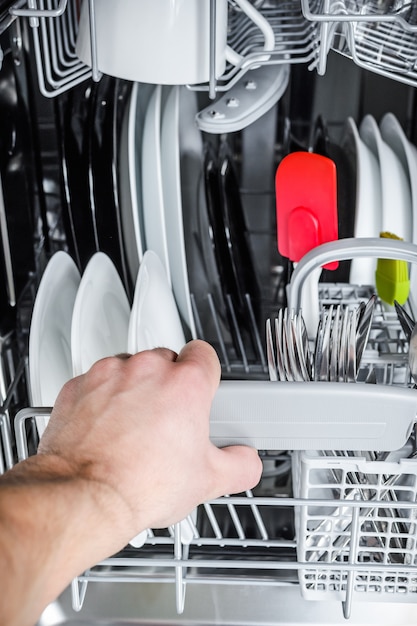 Photo man unloads clean dishes from the dishwasher