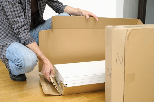 Man unpacking a cardboard box with furniture