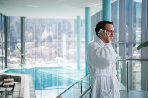 L'uomo usa il cellulare presso la spa dell'hotel di lusso vicino alla piscina