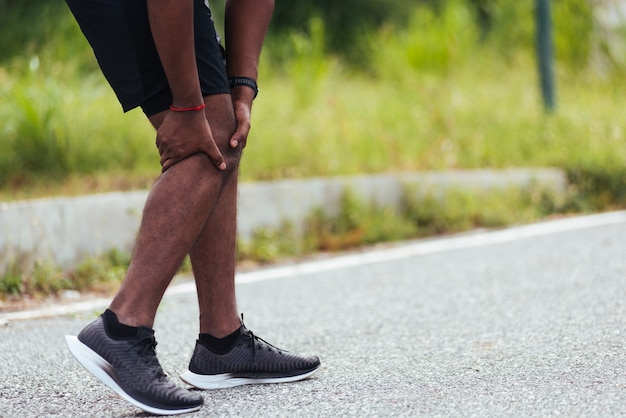 남자는 달리는 동안 무릎 통증을 잡고 손을 사용합니다.