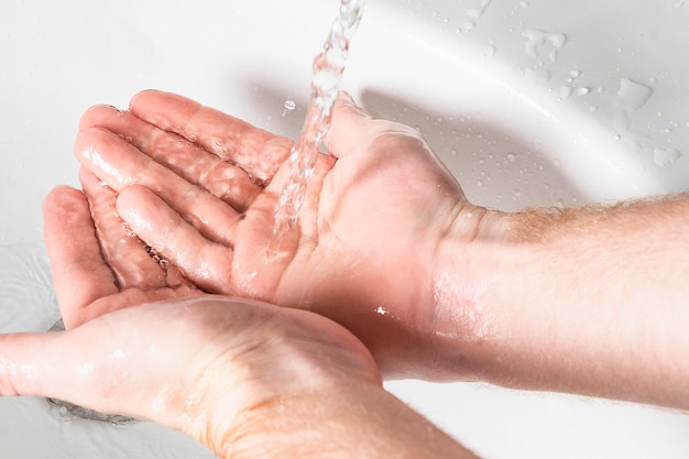 Photo man use soap and washing hands under the water tap. hygiene concept hand detail.