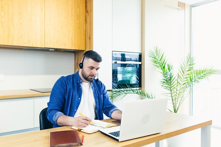 फोटो the man uses a headset with a microphone makes an online video call for consultations with the help of a laptop works at home