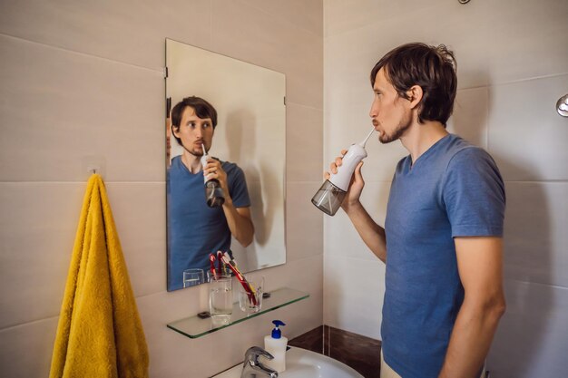 A man uses an oral irrigator in his bathroom