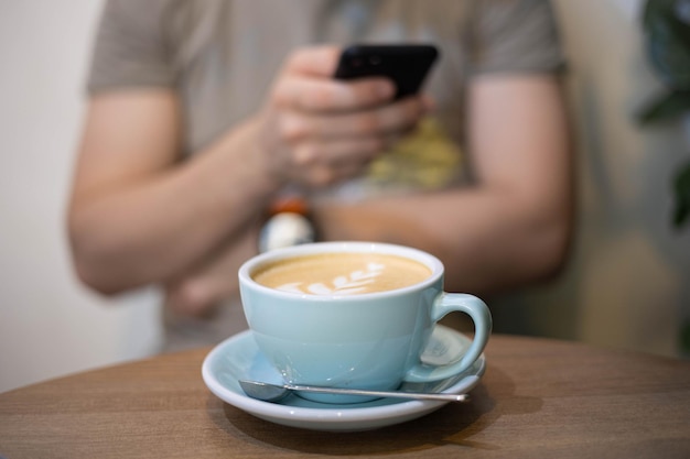 男はカフェで電話を使ってコーヒーを飲みます。