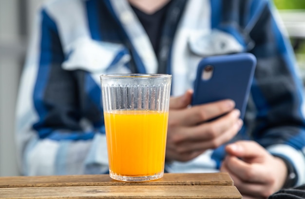 A man uses a smartphone and drinks orange juice