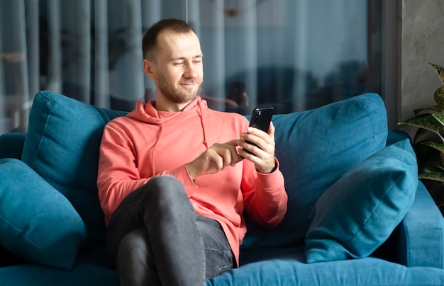 a man uses a smartphone on his home couch while relaxing at home applications calls 