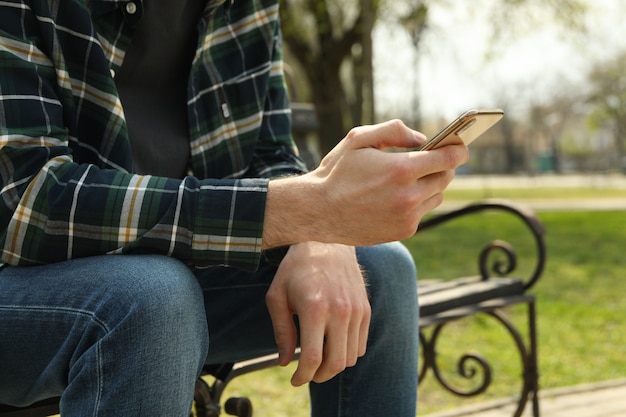 男は公園のベンチに座っているスマートフォンを使用して