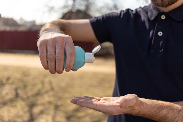 Man using bottle of antibacterial sanitizer