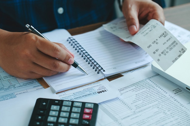 man using calculate domestic bills on wooden desk in office and business working background