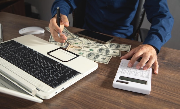 Man using calculator with a money and computer on the
table