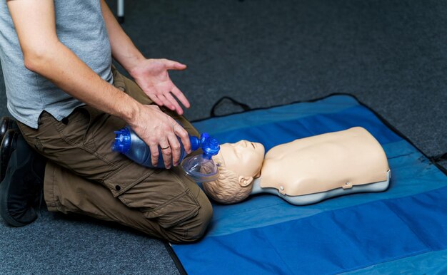 Photo man using cpr technique on dummy in first aid class. oxigen mask on medical doll.