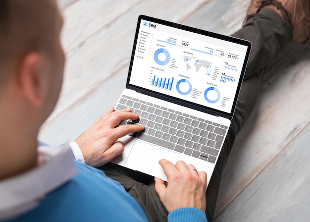 Photo man using crm software on laptop with graphs and charts showing sales data for his business