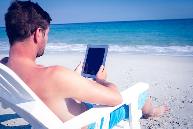 Man using digital tablet on deck chair at the beach