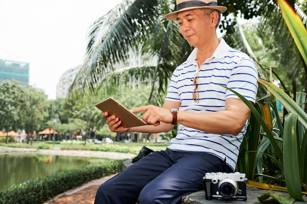 Человек с помощью цифрового планшета на открытом воздухе