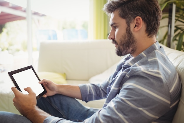 Man using digital tablet while relaxing on sofa