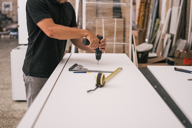 Man using an electric drill in a surface in a workshop