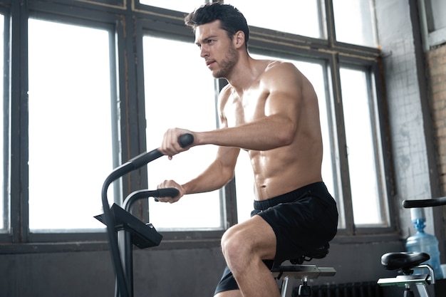 Man using exercise bike at the gym. Fitness male using air bike for cardio workout at Functional training gym.