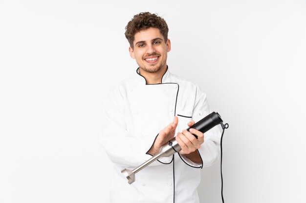 Man using hand blender on white wall applauding