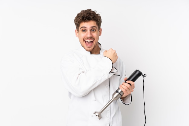 Man using hand blender on white wall celebrating a victory