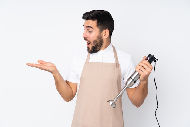 Man using hand blender on white wall holding blank space on the palm