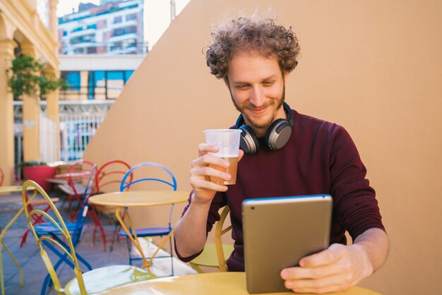 ビールを飲みながら彼のデジタルタブレットを使用している人。