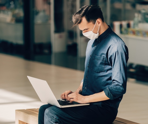 Man using his laptop while sitting on a bench