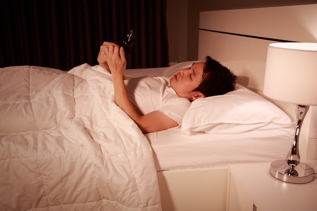 man using his mobile phone in bed at night