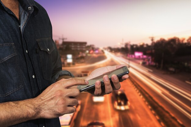 Uomo che usando la sua strada della luce notturna del telefono cellulare