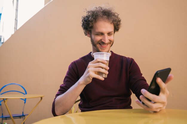 Uomo che per mezzo del suo telefono cellulare mentre bevendo birra