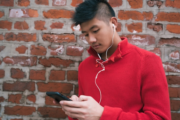 イヤホンで彼の携帯電話を使用している人。