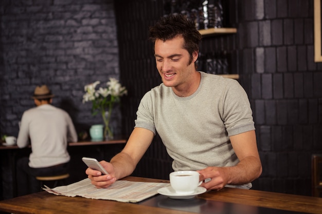 彼のスマートフォンを使用して、コーヒーを飲む人