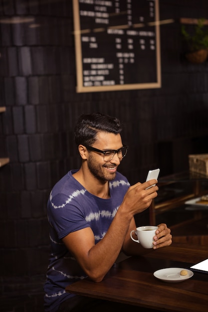 Man using his smartphone and drinking coffee