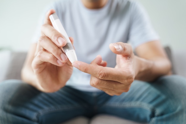 Man using lancet on finger for checking blood sugar level by Glucose meter, diabetes concept