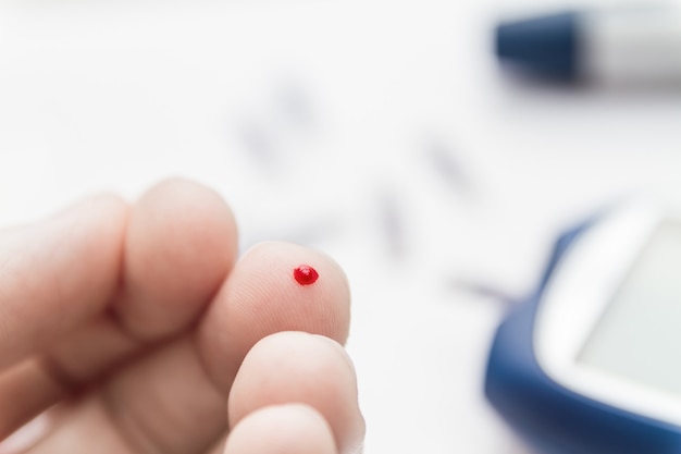 Man using lancet pen on finger to checking blood sugar level by blood glucose meter