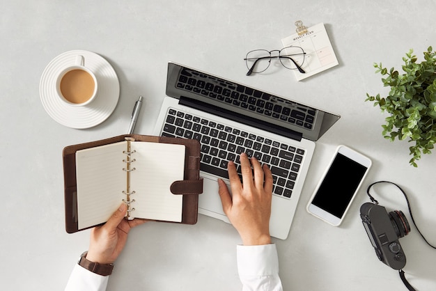 Man using laptop and holding diary at table