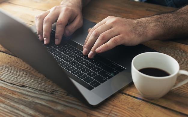 Man using laptop in home office Male hands typing on keyboard