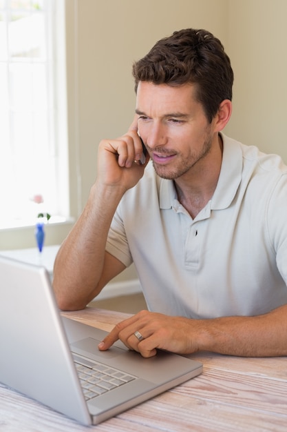 Man using laptop and mobile phone at home