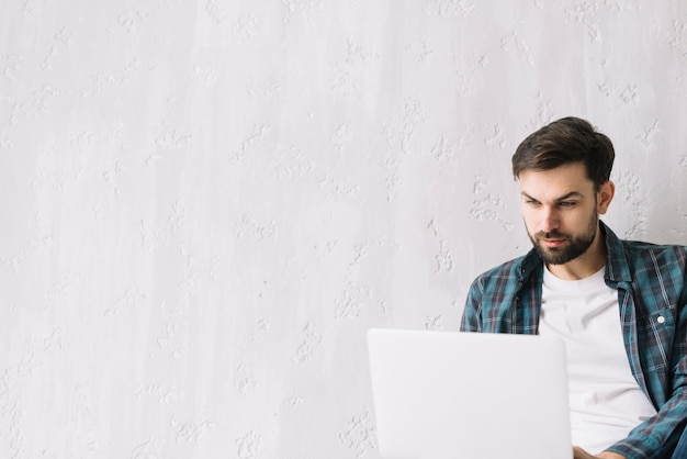 Photo man using laptop near wall