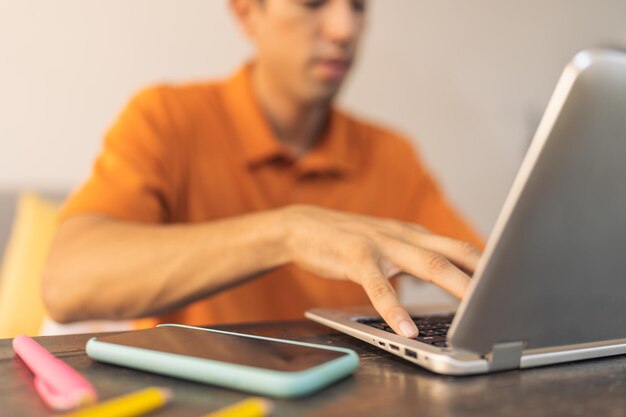 Photo man using laptop sitting on a desk with a mobile