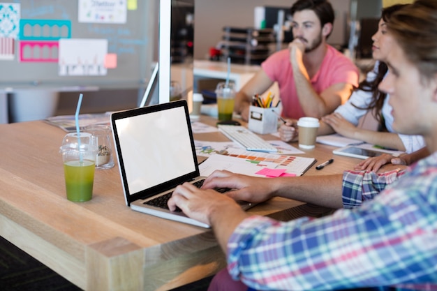 Man using laptop while working with his team in office