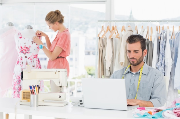 Man using laptop with fashion designer working at studio