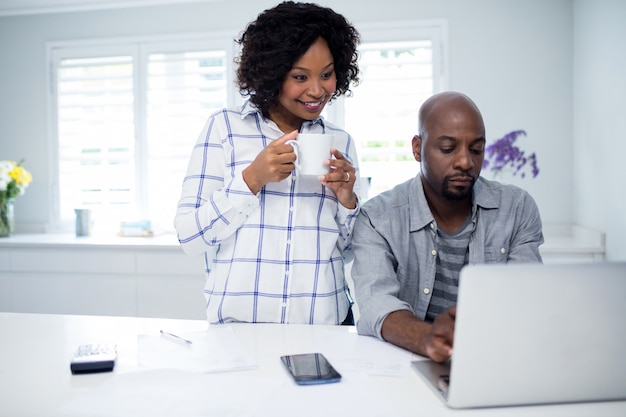 Man using laptop with woman holding coffee cup