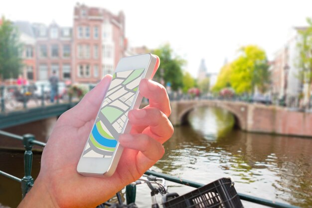 Man using map app on phone against canal in amsterdam