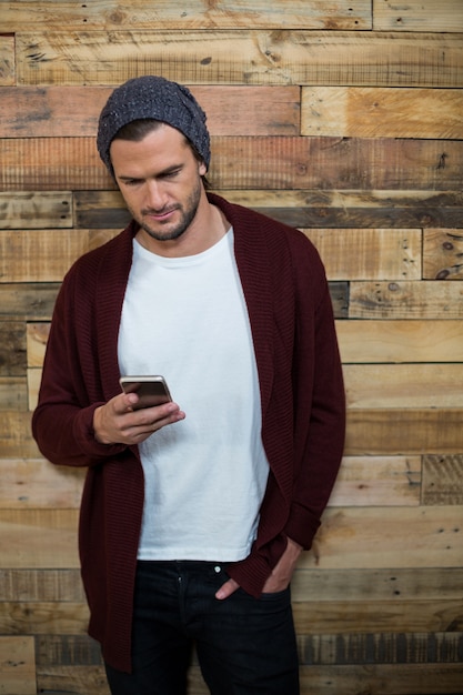 Man using mobile phone against wooden wall